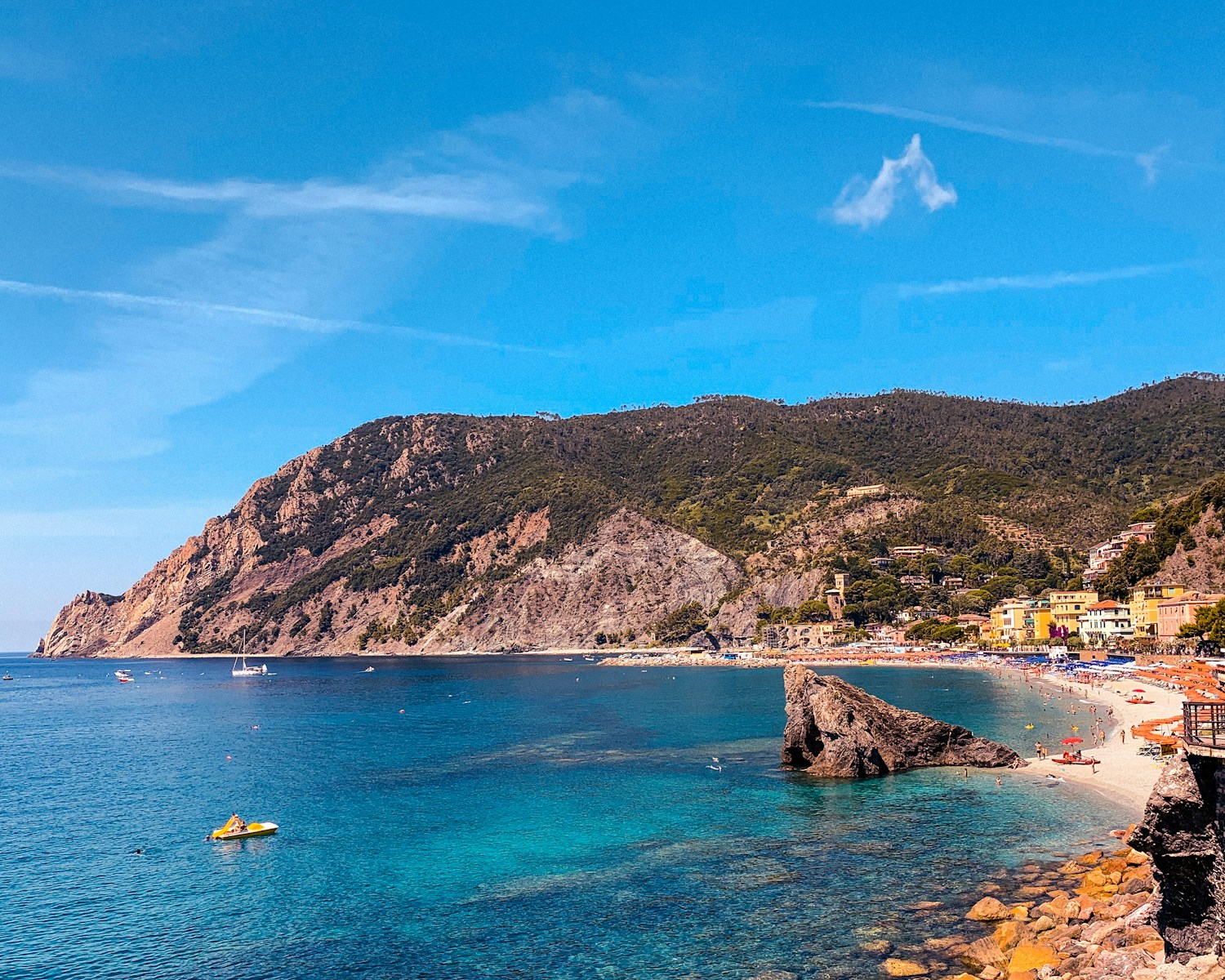 people riding on boat on sea near mountain under blue sky during daytime